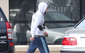 A man walks past a broken window from a police terror raid at a house in Melbourne, where police made one of several arrests.