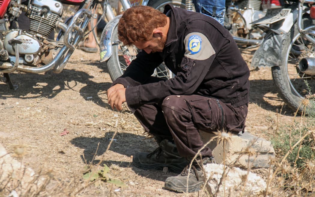 A member of the Syrian civil defence volunteers, also known as the White Helmets, mourns as colleagues bury his fellow comrades.
