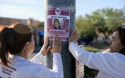TUCSON, ARIZONA - FEBRUARY 24: Rachel Navarro (L) and Lidia Hernandez, who are part of the Madres Buscadoras De Sonora (Searching Mothers of Sonora), place a flyer that reads, ‘Nancy Guthrie Desparecida’ (Disappeared) on a pole about a mile from Nancy Guthrie’s residence on February 24, 2026, in Tucson, Arizona. The organization is dedicated to finding lost people in the Mexican state of Sonora and, sometimes, in other areas. Law enforcement officials continue to search for Nancy Guthrie, the 84-year-old mother of U.S. journalist and television host Savannah Guthrie, after she went missing from her home on the morning of February 1st. Savannah Guthrie announced a $1 million reward for anyone who helps find her mother.   Joe Raedle/Getty Images/AFP (Photo by JOE RAEDLE / GETTY IMAGES NORTH AMERICA / Getty Images via AFP)