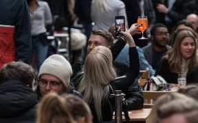 A woman takes a picture of her drink in Soho as outdoor hospitality venues open their premises to customers after being closed for over three months under coronavirus lockdown.