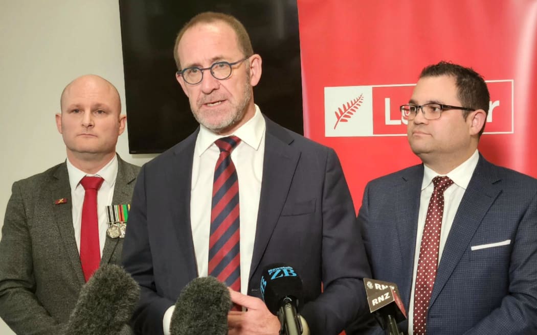 Labour's Defence spokesperson Andrew Little announces the party's policy to have Defence Force pay rates set independently of the government, flanked by current Labour MPs Dan Rosewarne (L) and Tangi Utikere (R).