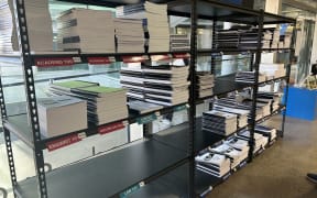 Picture of a bookshelf in the UBIQ bookstore. It shows some piles of coursebooks, while some spaces are empty.