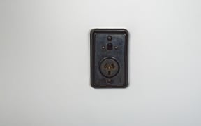 Old fashioned bakelite power socket with on/off switch on a white plaster wall
