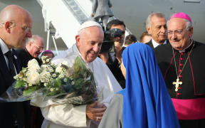 Pope Francis at New York's John F. Kennedy International Airport on September 26, 2015, greeted by nuns from the Monastery of the Precious Blood in Brooklyn, who presented the pontiff with a gift of flowers. Bishop Nicholas DiMarzio (R) of Brooklyn