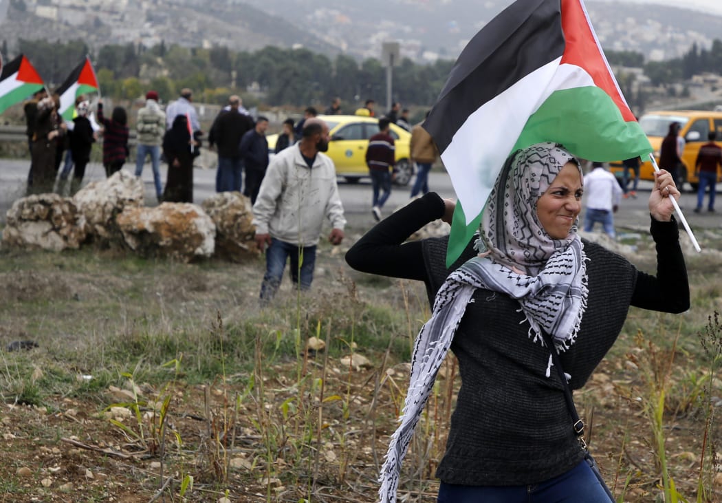 A Palestinian protester waves a Palestinian flag as she throws a stone during clashes with Israeli security forces near the Huwara checkpoint in the West Bank on Wednesday.