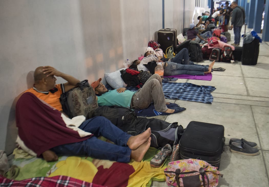 Venezuelan nationals spend the night sleeping on the sidewalk at the binational border attention centre (CEBAF) in Tumbes, northern Peru on August 24, 2018.