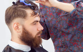 barber cutting hair with scissors and comb. side view of man in barber shop.