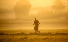 24 July 2019, Baden-Wuerttemberg, Unlingen: A jogger runs towards the sun shortly after sunrise. Temperatures of up to 38 degrees are predicted for the course of the day. Photo: Thomas Warnack/dpa (Photo by Thomas Warnack / DPA / dpa Picture-Alliance via AFP)