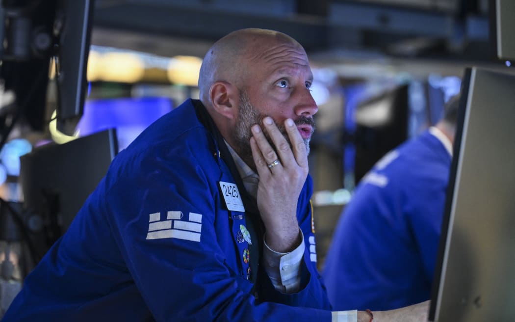 A trader works on the floor of the New York Stock Exchange (NYSE) at the opening bell on April 21, 2025, in New York City, Wall Street stocks opened lower Monday amid lingering uncertainty over President Trump's trade policy as markets looked ahead to major earnings later in the week. China on Monday hit out at other countries negotiating trade deals with the United States at Beijing's expense, vowing countermeasures against those who "appease" Washington. (Photo by ANGELA WEISS / AFP)