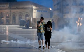 A man and a woman cover their noses from teargas fumes during a protest in Montpellier, southern France on June 30, 2023, over the shooting of a teenage driver by French police in a Paris suburb on June 27. French President Emmanuel Macron has announced measures including more police and urged parents to keep minors off the streets as he battled to contain nightly riots over a teenager's fatal shooting by an officer in a traffic stop. (Photo by Sylvain THOMAS / AFP)