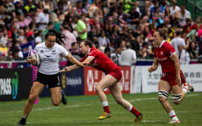 New Zealand’s Portia Woodman-Wickliffe (L) tries to break the tackle of Canada’s Julia Greenshields (C)  during their match on the second day at the Hong Kong Sevens.