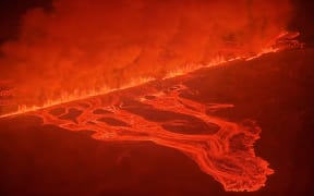 This handout picture released by the Icelandic Coast Guard on February 8, 2024 shows billowing smoke and flowing lava pouring out of a new fissure during a new volcanic eruption on the outskirts of the evacuated town of Grindavik, western Iceland. A volcanic eruption started on the Reykjanes peninsula in southwestern Iceland on Thursday, the third to hit the area since December, authorities said. (Photo by HANDOUT / Icelandic Coast Guard / AFP)