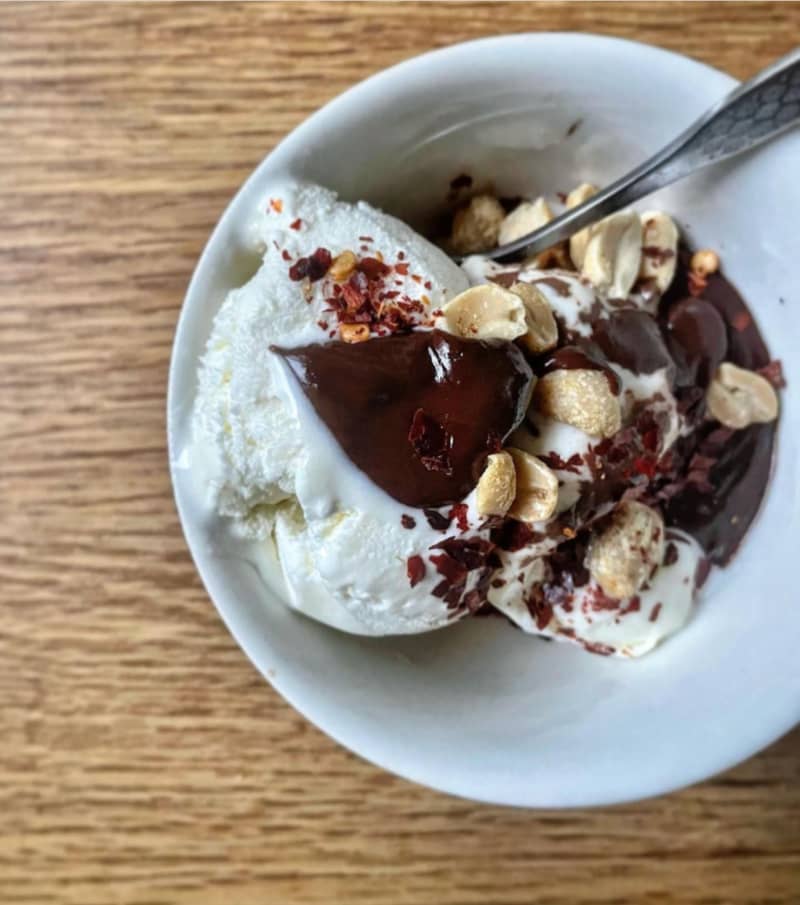 A bowl of Lucy Corry's Famous Vanilla Ice Cream With Chocolate Sauce and Spicy, Salty Nuts