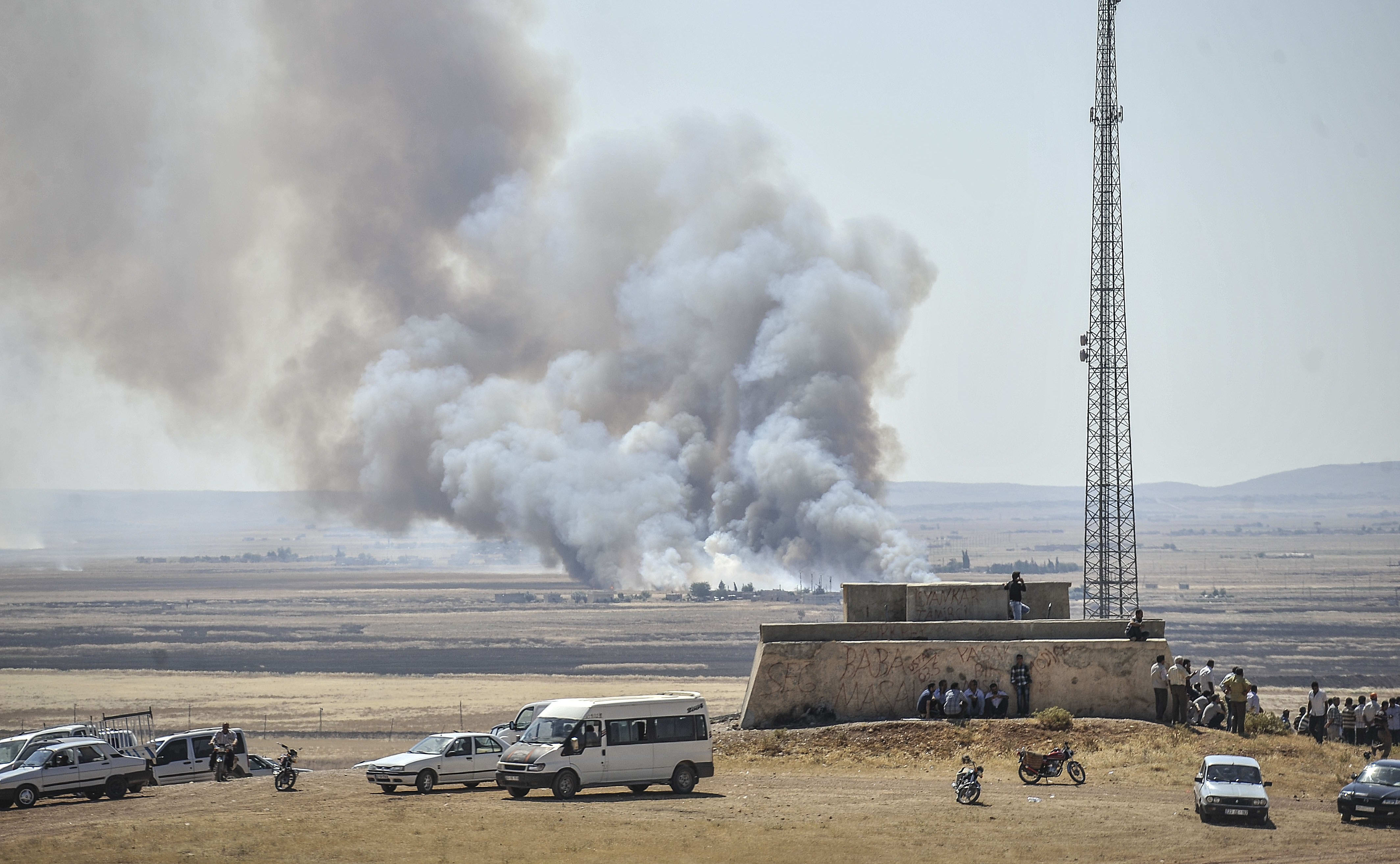 Smoke rises as Islamic State fighters and Kurdish armed groups clash in the Syria-Turkey border town of Kobane on 26 June.