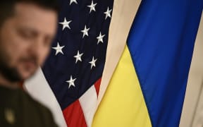 The US and Ukrainian flags appear behind Ukraine's President Volodymyr Zelensky during a press conference with US President Joe Biden at the East Room of the White House, in Washington, DC, on December 21, 2022. (Photo by Brendan SMIALOWSKI / AFP)