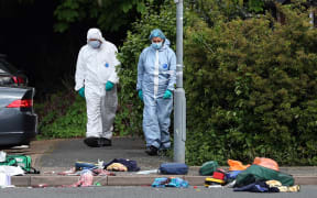 Police forensic officers examine the crime scene in Hainault, east of London on April 30, 2024, where a 36-year-old man wielding a sword was arrested following an attack on members of the public and two police officers. A 13-year-old boy died on Tuesday after five people, including two police officers, were wounded by a man wielding a sword in east London, police said. "It's with great sadness that one of those injured in this incident, a 13-year-old boy, has died from their injuries," Chief Superintendent Stuart Bell, from the Metropolitan Police, told reporters. (Photo by Adrian DENNIS / AFP)