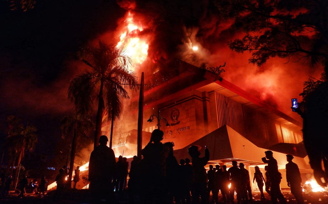 The building of Makassar City Regional House of Representatives is set on fire during a protest in Makassar, South Sulawesi, on August 29, 2025. Indonesian police fired tear gas on August 29 at hundreds of protesters rallying in the capital over the death of a motorcycle taxi driver, hours after the country's president promised to investigate the incident. Clashes between protesters and police broke out on August 28 over calls for higher wages and perceived lavish perks for lawmakers, as public discontent grows over the government's handling of the economy. (Photo by DAENG MANSUR / AFP)