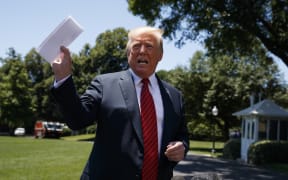 President Donald Trump speaks in Washington to reporters while waving around a paper with details of the US immigration deal with Mexico.