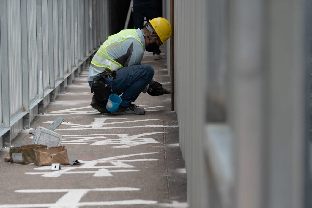 A construction worker uses metal sheeting to cover up one of the last public tributes in Hong Kong to the deadly 1989 Tiananmen Square crackdown which has adorned a campus footbridge at the University of Hong Kong (HKU) for over three decades.