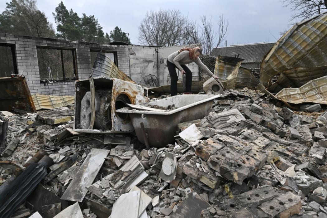 A woman examines the debris of her destroyed house in the village of Rusaniv, in the Kyiv region on 16 April.