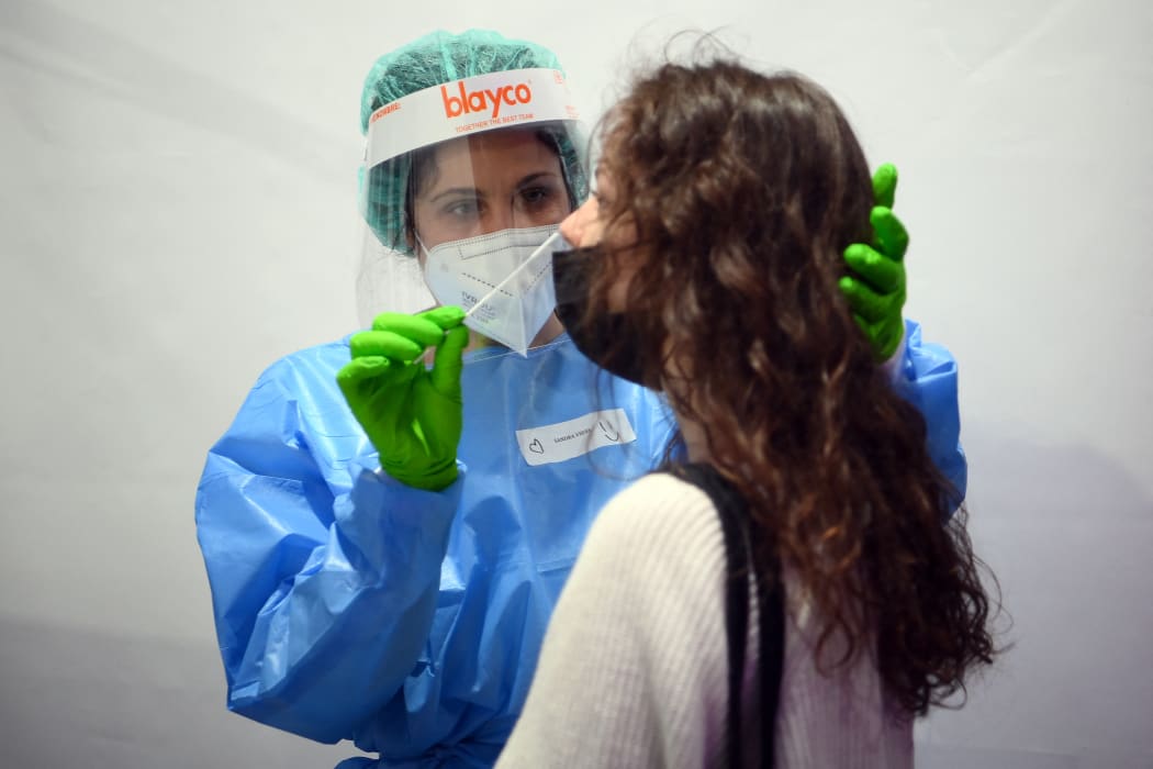 A health worker collects a swab sample for Rapid Antigen Test (RAT) for the Covid-19 coronavirus from a woman who later on March 27, 2021 will attend with other 5,000 people a rock music concert in Barcelona d