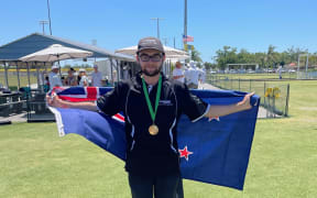 Photo of Levi Franks, a croquet player from Christchurch New Zealand, holding a New Zealand flag.