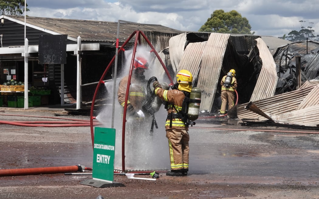 A firefighter is washed down in a decontamination shower. Photo: RNZ / Peter de Graaf