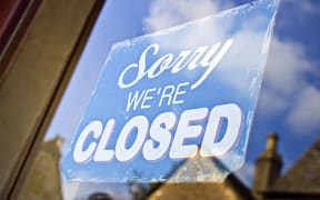 A closed sign hanging in the glass doorway of a shop in the UK