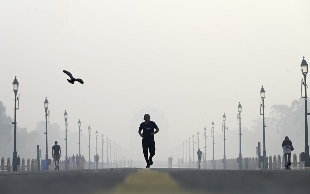 A man jogs along the road in front of India Gate amid smoggy conditions in New Delhi on November 1, 2022. (Photo by Money SHARMA / AFP)