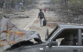 A resident walks along a street in Mariupol, trying to flee the conflict.