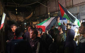 People celebrate along a street at Deir el-Balah in the central Gaza Strip, on 15 January, 2025, amid the ongoing war in the Palestinian territory between Israel and Hamas. Crowds of Gazans chanted and embraced on January 15 as news spread that a ceasefire and hostage release deal had been reached between Israel and Hamas aimed at ending more than 15 months of war in the Palestinian territory.