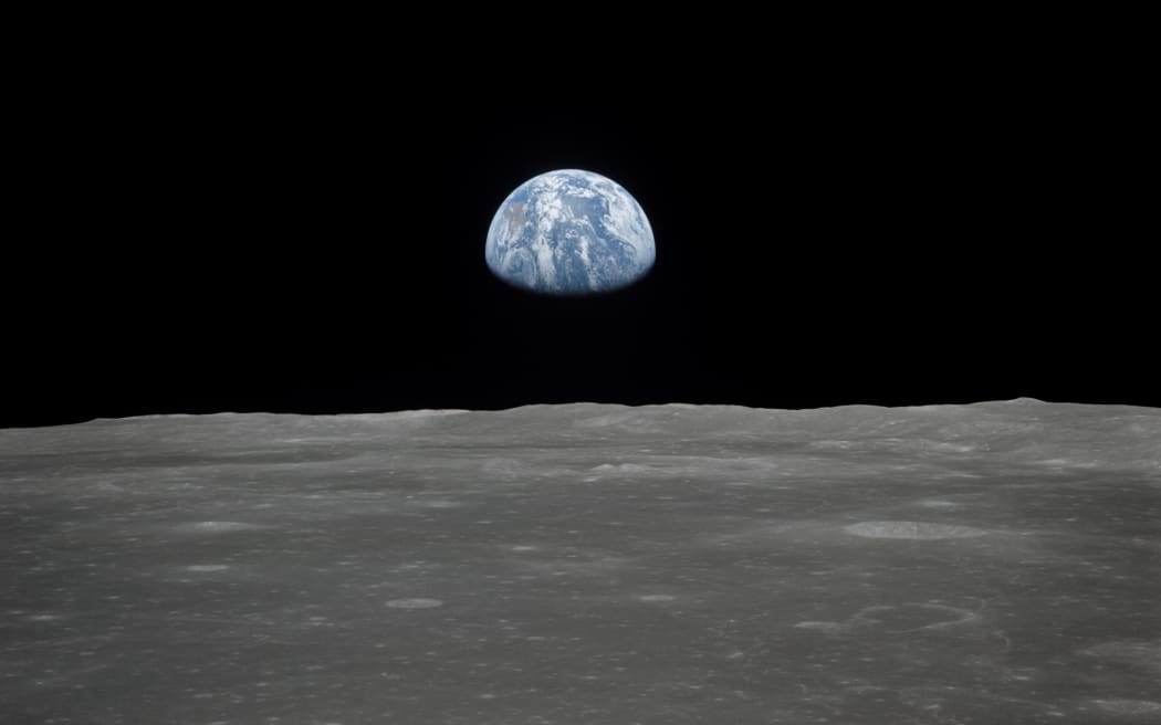 This July 1969 NASA file photo obtained July 16, 2019 shows a file view of Earth rising over the Moon's horizon taken from the Apollo 11 spacecraft. - The lunar terrain pictured is in the area of Smyth's Sea on the nearside.