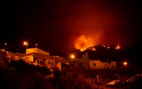 A picture taken in the night of August 19, 2023 shows the fronts of the forest fire on hills above houses, in the Guimar valley on the Canary Island of Tenerife. The blaze, which officials say is the most "complex fire" to hit the Canary Islands in 40 years, broke out on August 15 in a mountainous area of northeastern Tenerife. 225 firefighters are struggling against the ferocious blaze which has so far destroyed nearly 5,000 hectares (more than 12,000 acres) of land, has a perimeter of 50 kilometres (30 miles) and led to the evacuation and/or confinement of some 7,600 people from nine population centers. (Photo by DESIREE MARTIN / AFP)