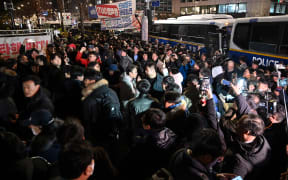 People gather in front of the main gate of the National Assembly in Seoul, South Korea on December 4, 2024, after President Yoon Suk Yeol declared emergency martial law. - South Korea's President Yoon Suk Yeol on December 3 declared emergency martial law, saying the step was necessary to protect the country from "communist forces" amid parliamentary wrangling over a budget bill. (Photo by JUNG YEON-JE / AFP)