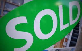 A sold sticker on a real estate sign outside a house in Auckland.
