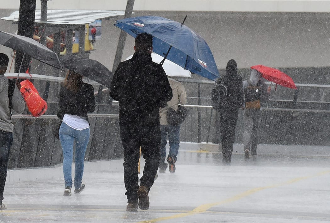Pedestrians walk through rainy weather in Brisbane on Friday.