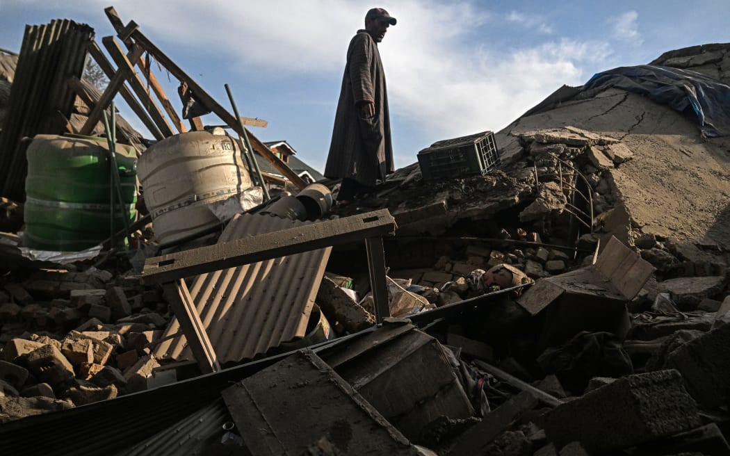 A man walks through the debris of a demolished house related to the family of Ahsan Ul Haq Sheikh, who is suspected of involvement in the Pahalgam tourist attack, in Murran village of Pulwama, south of Srinagar, on April 26, 2025. Soldiers in Indian-administered Kashmir on April 25 blew up the family homes of two men who police allege were among a gang that carried out the region's deadliest attack against civilians for decades. (Photo by Tauseef MUSTAFA / AFP)