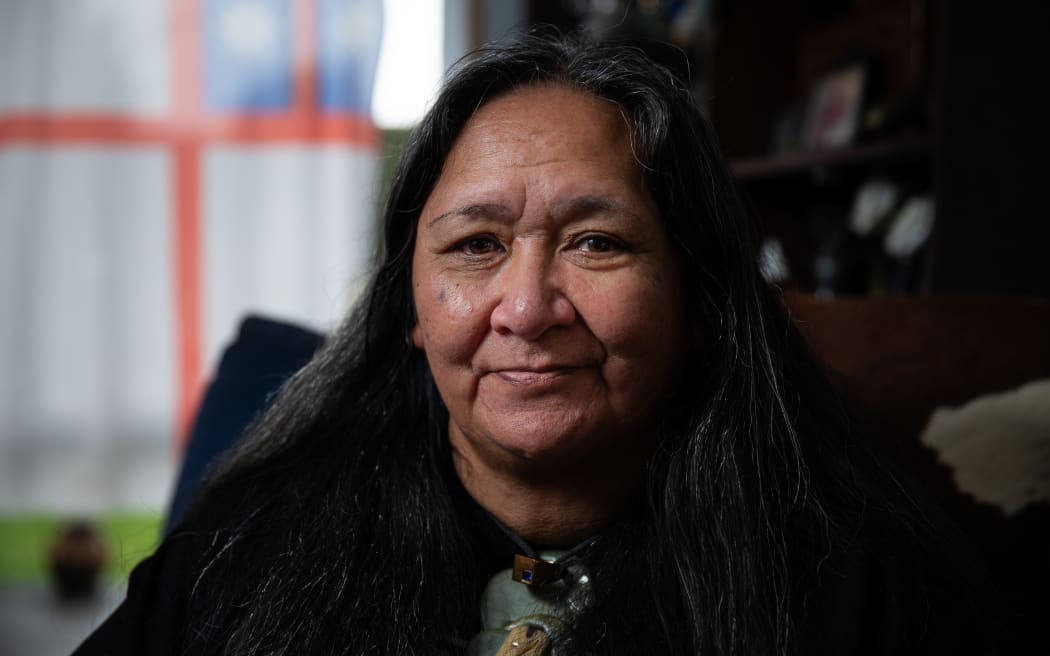 Joyce Harris photographed in her home. A United Tribes flag hangs behind her.