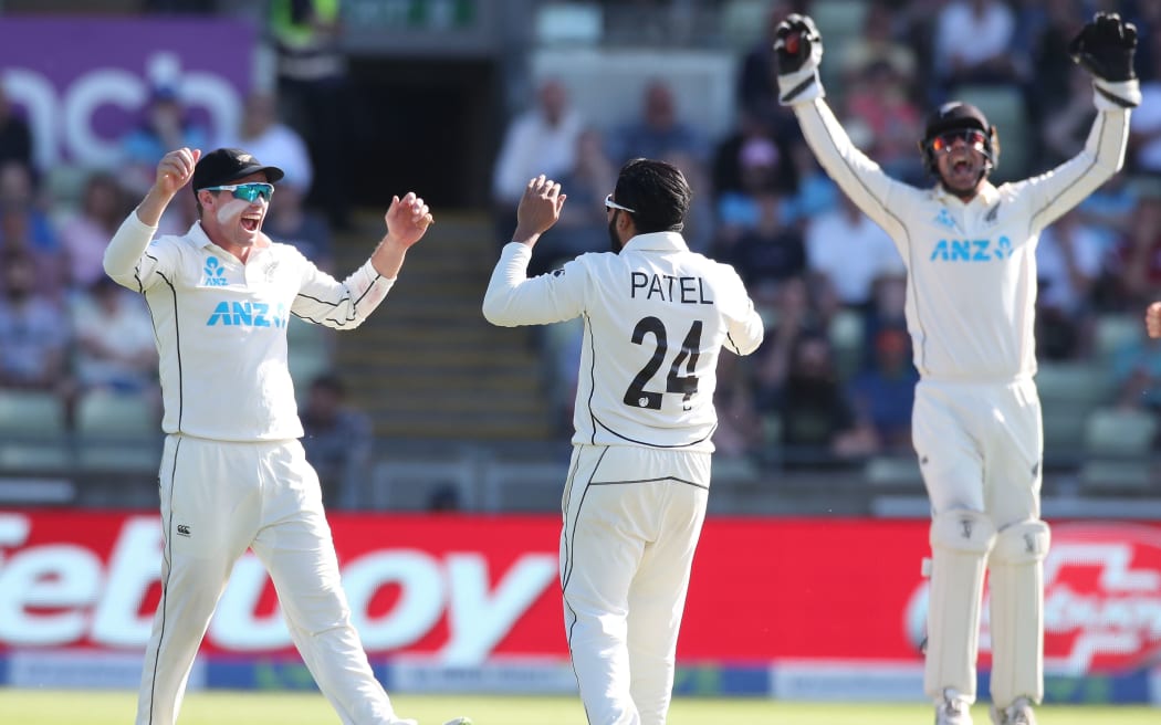 Ajaz Patel celebrates taking the wicket of Joe Root with Tom Latham (left) and wicketkeeper Tom Blundell.