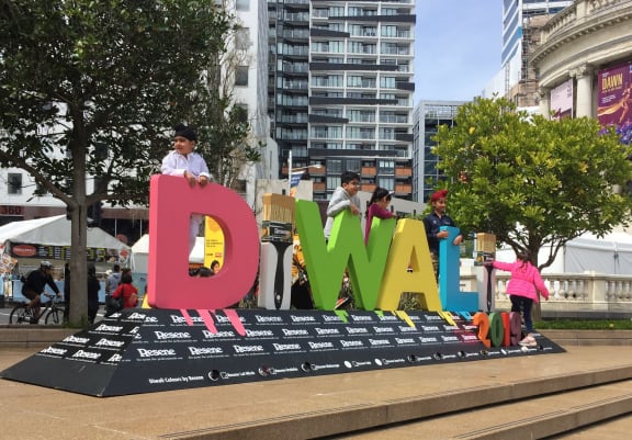 Children clamber over Diwali sign to pose for photograhs.