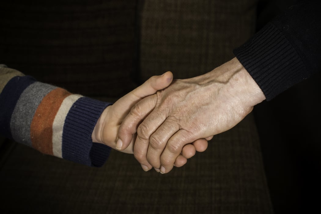 An adult holding a child's hand