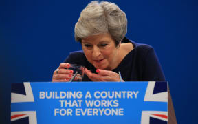 Theresa May splutters as she drinks water while losing her voice during her keynote speech.