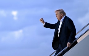 US President Donald Trump raises a fist as he steps off Air Force One at Palm Beach International Airport in West Palm Beach, Florida, on April 11, 2025. Trump is heading to Palm Beach to spend the weekend at his Mar-a-Lago resort. (Photo by Mandel NGAN / AFP)