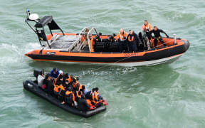 This handout photograph taken and released by the French Marine Nationale on August 5, 2019 shows migrants sitting in an inflatable dinghy rescued by French coast guards while trying to cross the Channel between France and Britain, off the coast of Graveline and the Cap Griz-Nez, on August 5, 2019.