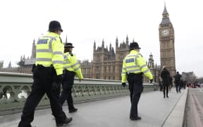 Police patrol across Westminster Bridge toward the Houses of Parliament a day after the attack.