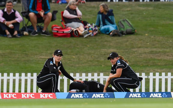 White Fern bowler Lea Tahuhu is injured with Amy Satterthwaite and Frances Mackay looking on, 2021.