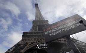 A picture taken on March 14, 2020 near the Eiffel tower in Paris shows a board informing of the monument's closure as a precaution against the coronavirus.
