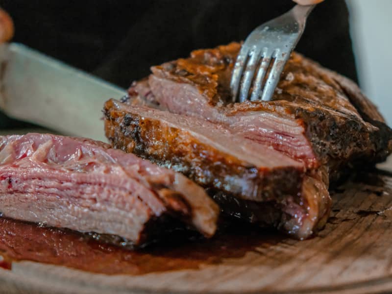 person cutting lamb with knife and fork