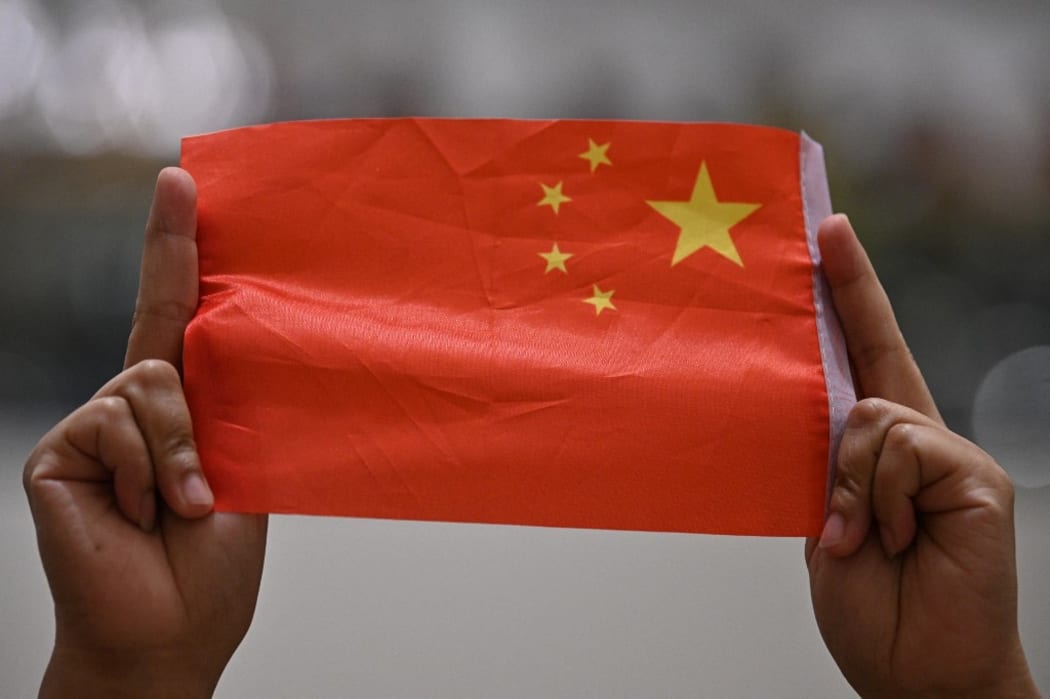 A woman holds up a Chinese flag during a pro-Beijing flash mob at the Pacific Place shopping mall in Hong Kong