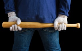 Man holding a baseball bat on black background